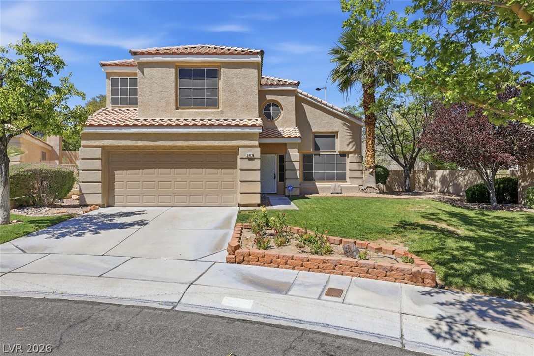 Front exterior of 2421 Bloomington Dr, Las Vegas — two-story stucco home with tile roof, two-car garage, and a rose planter along the walkway.