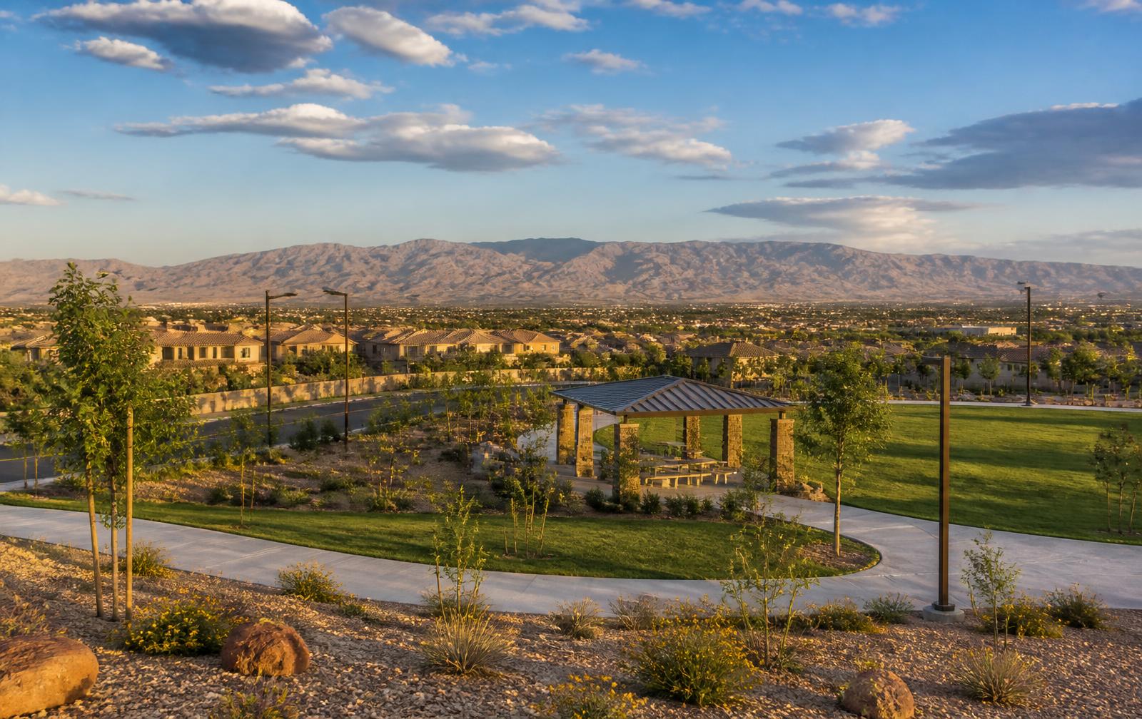 North Las Vegas neighborhood park with a shade pavilion and lawn, homes and a mountain range in the distance.